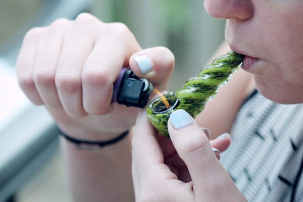 someone smoking cannabis in a glass pipe